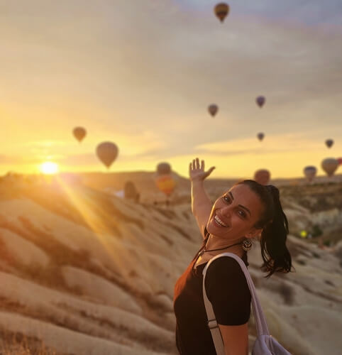 Aşk Vadisi’nde gün doğumunda sıcak hava balonları eşliğinde poz veren ve yazının yazarı olan kadın gezgin